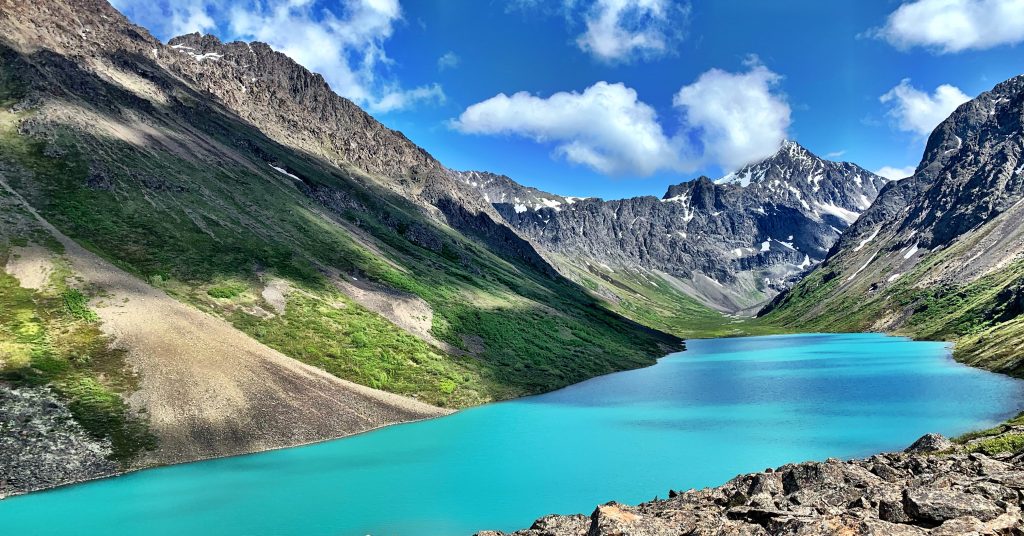 Turquoise alpine lake surrounded by rugged Alaska mountains.